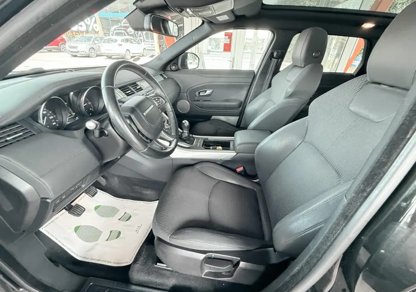 Intérieur noir du Range Rover Evoque 2017 vu côté conducteur, avec volant, sièges et tableau de bord visibles.