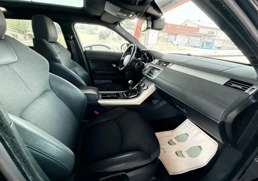 Intérieur noir du Range Rover Evoque 2017 vu côté passager, avec tableau de bord et sièges avant en tissu et cuir.