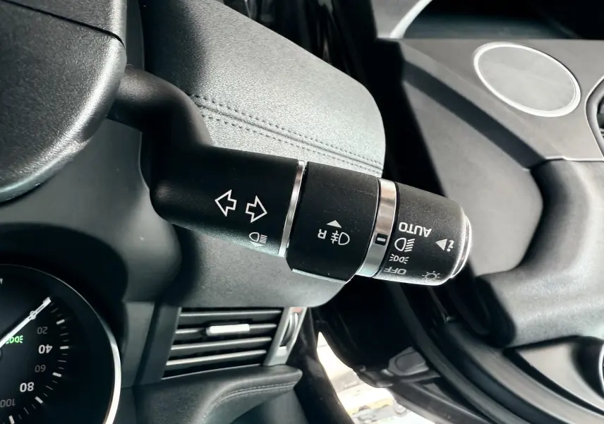 Gros plan sur la commande des feux et clignotants noire dans l'habitacle du Range Rover Evoque noir de 2017.