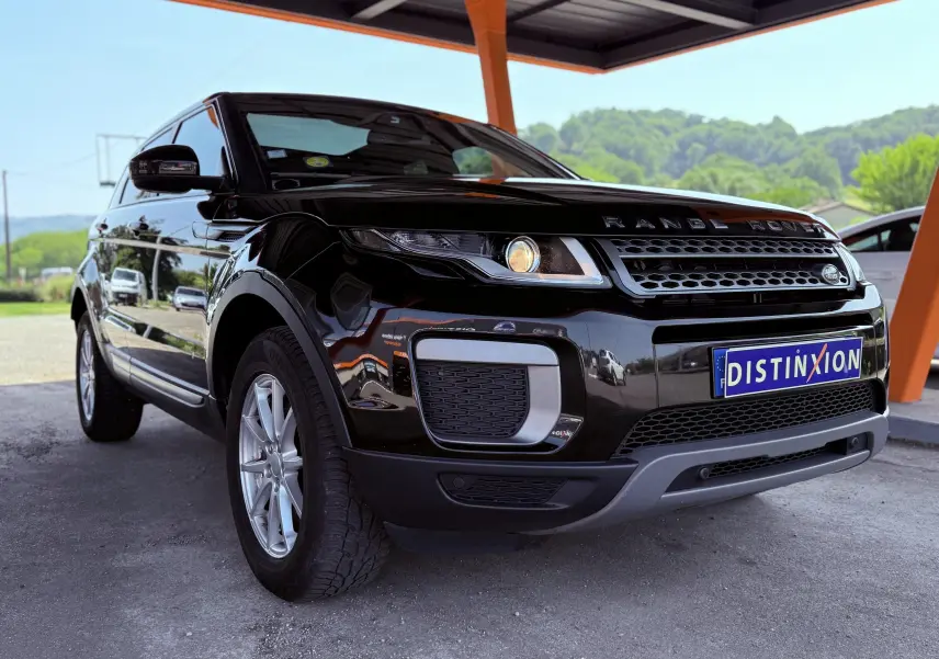 Range Rover Evoque noir vu en 3/4 avant droit sous un abri avec plaque d'immatriculation Distinxion visible.