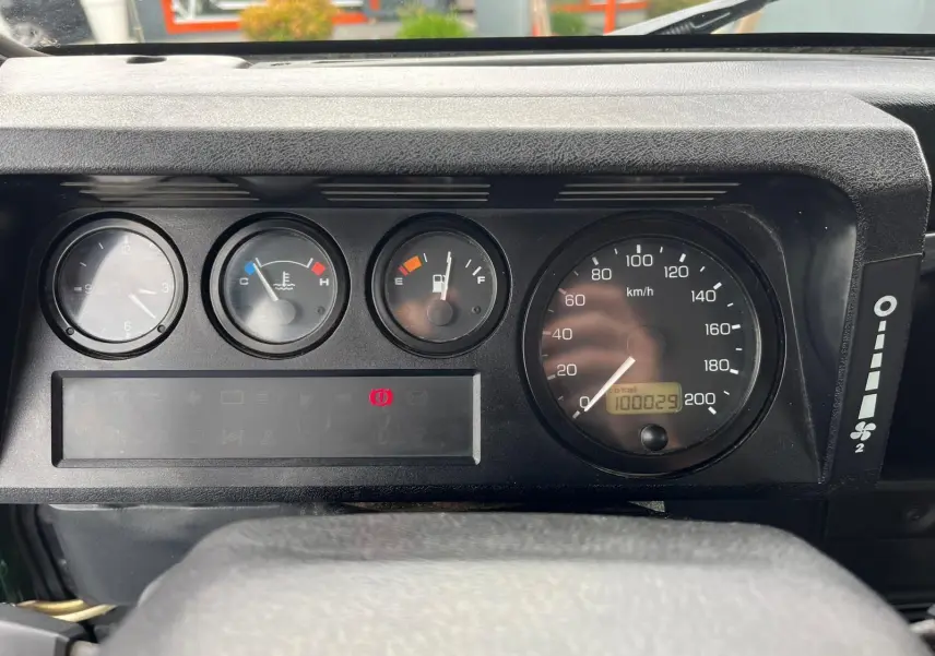 Tableau de bord du Land Rover Defender 90 2004, montrant les compteurs analogiques et l'odomètre à 100029 km.