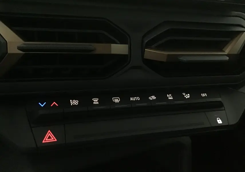 Panneau de commandes climatisation et alertes du tableau de bord du Dacia Duster 2025 kaki, avec touches rétroéclairées.