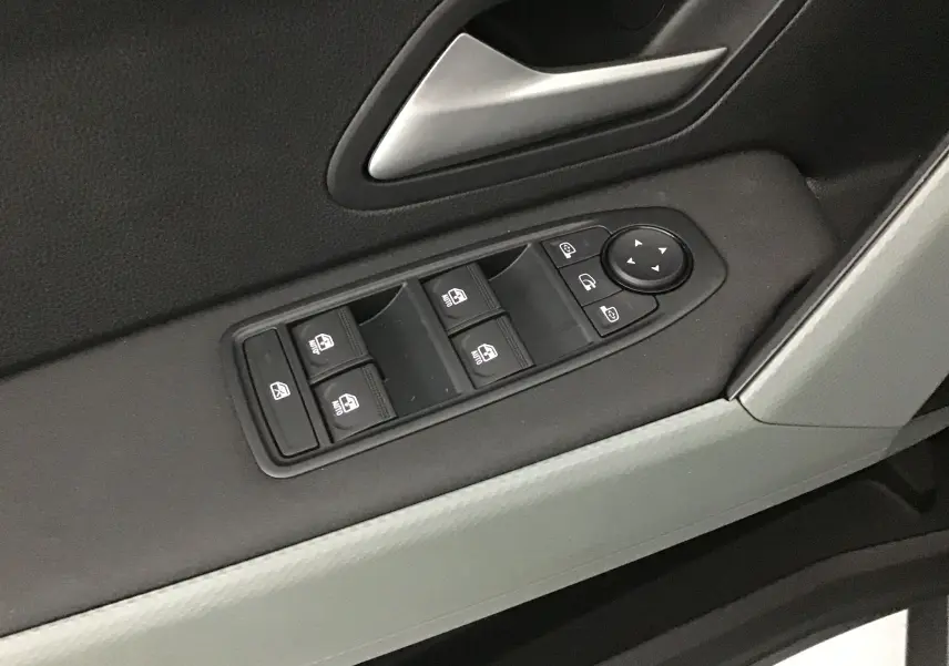 Gros plan sur les commandes des vitres électriques et rétroviseurs sur la porte côté gauche du Dacia Duster 2025.