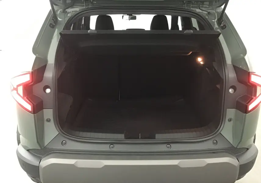 Coffre ouvert vu de l'arrière d'un Dacia Duster 2025 kaki lichen avec feux arrière allumés et intérieur spacieux.