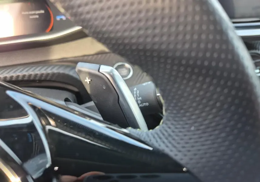 Gros plan sur la palette de changement de vitesse au volant du Peugeot 2008 Hybrid 145 e-DCS6 GT noir, intérieur moderne.