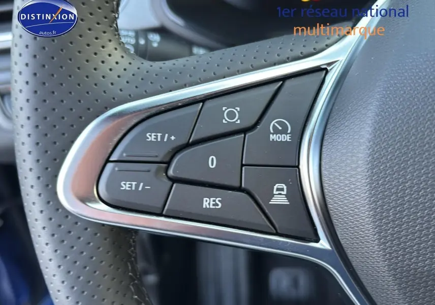 Gros plan sur les commandes multifonctions au volant perforé d’un Renault Captur bleu iron t/noir 2026.