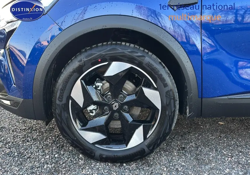 Gros plan sur la roue avant gauche avec jante alu noire et argent sur Renault Captur bleu iron t/noir.