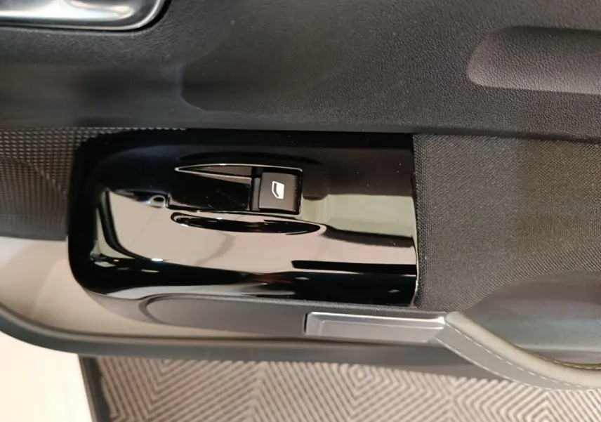 Gros plan sur le bouton de commande de la vitre électrique côté conducteur d'une Citroën C3 blanche de 2020.