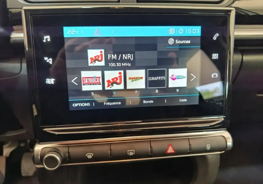 Écran tactile central de la Citroën C3 blanche, affichant les stations radio avec commandes en dessous.