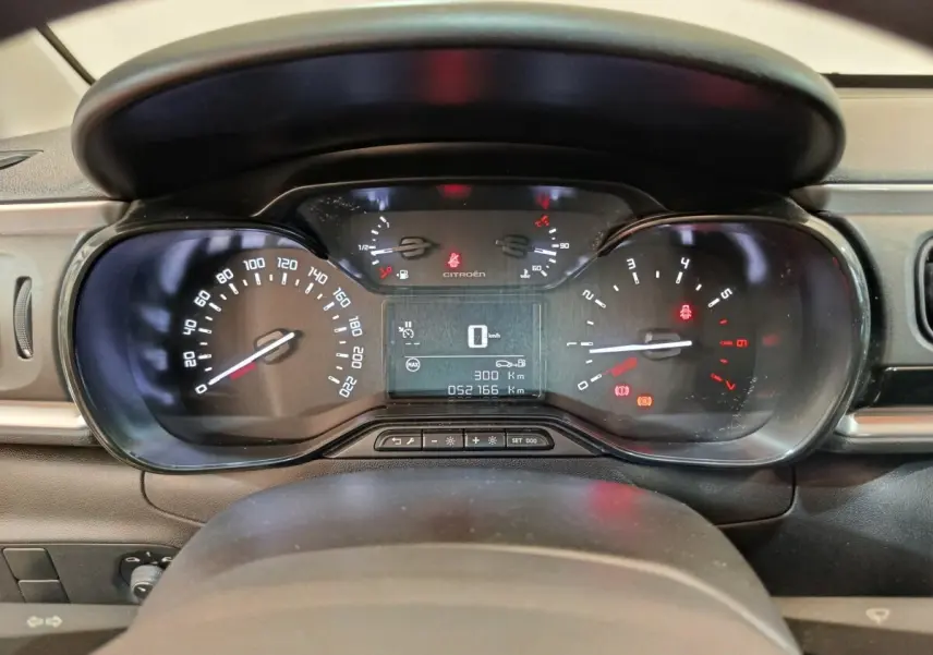 Vue rapprochée du tableau de bord numérique de la Citroën C3 blanche, affichant vitesse et jauges.