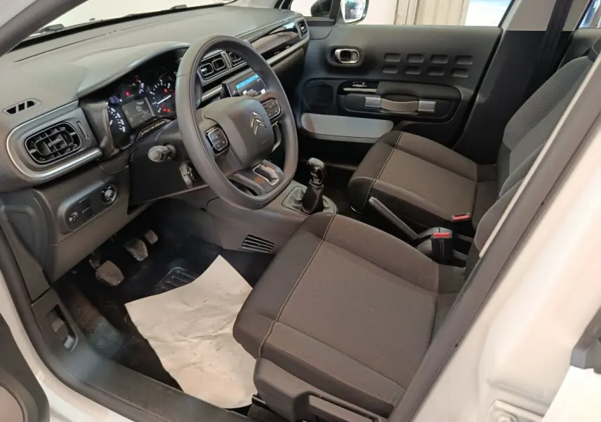 Vue intérieure côté conducteur de la Citroën C3 blanche 2020, volant multifonctions et sièges tissu noirs.