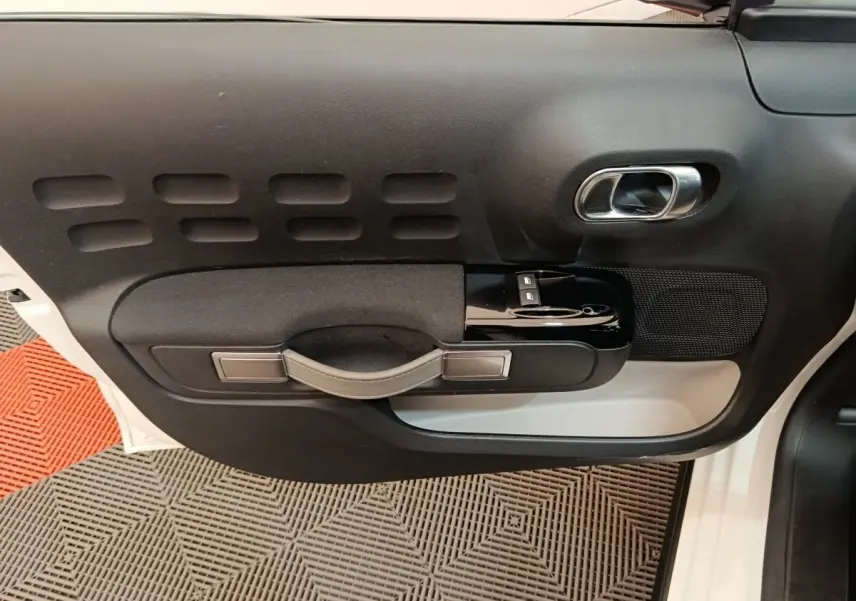 Vue rapprochée de la porte avant droite blanche d'une Citroën C3 2020 avec poignée noire et commandes de vitres.
