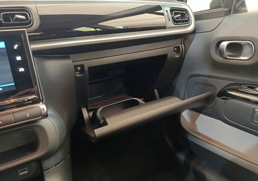 Intérieur de la Citroën C3 blanc, vue côté passager sur la boîte à gants ouverte et tableau de bord noir brillant.
