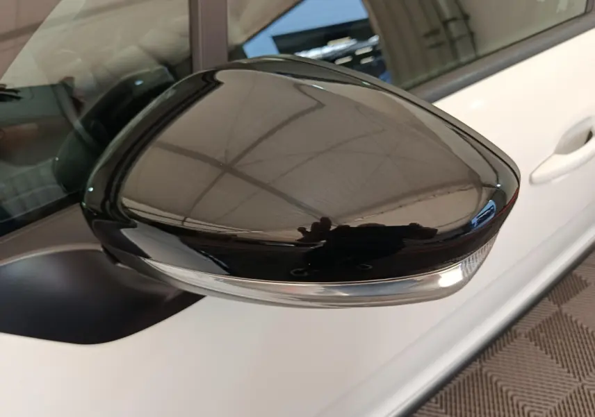 Rétroviseur extérieur droit noir brillant sur Citroën C3 blanche, vue rapprochée côté passager.