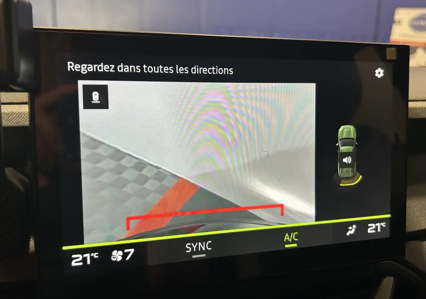 Écran intérieur affichant la caméra de recul et l’alerte de proximité sur un Dacia Bigster bleu Indigo, vue du tableau de bord.