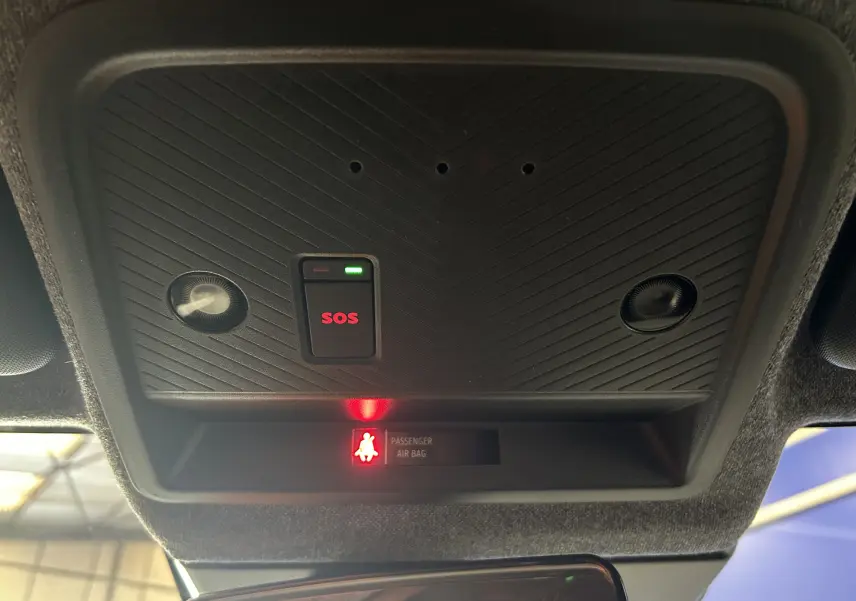 Vue intérieure du plafonnier avec bouton SOS et témoin d'airbag passager allumé sur Dacia Bigster bleu indigo.