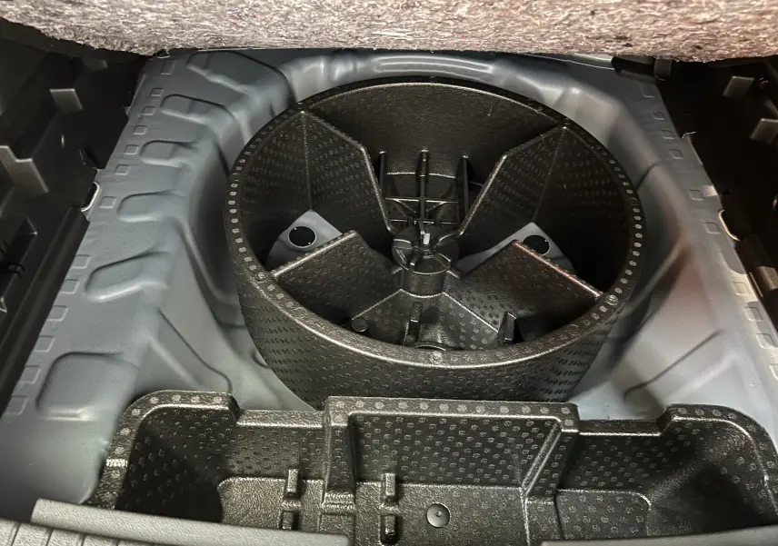 Coffre ouvert montrant le rangement sous plancher avec compartiment rond pour roue de secours du Dacia Bigster 2026.