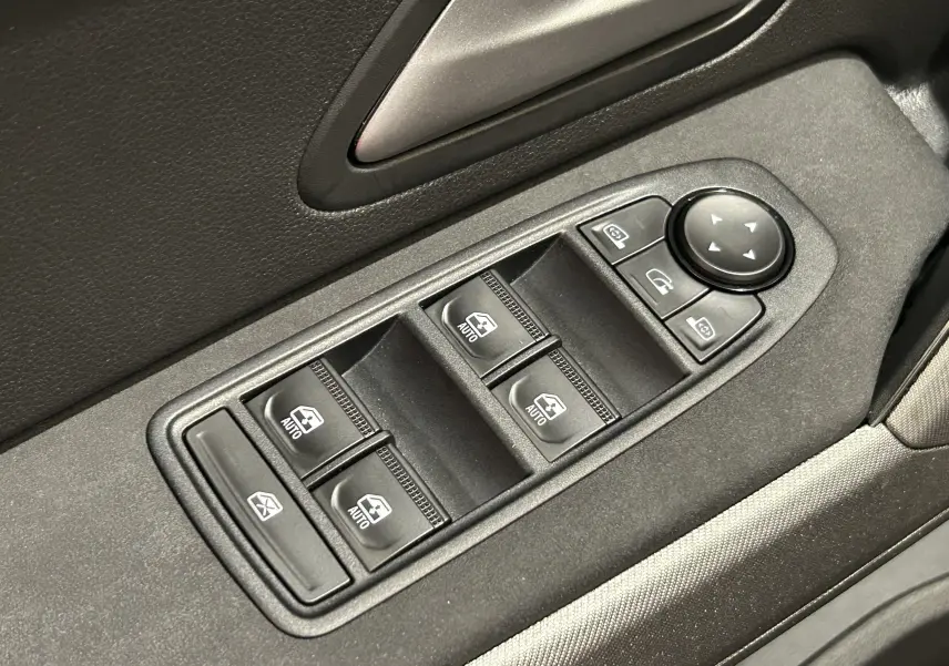 Gros plan sur les commandes de lève-vitres et réglage des rétroviseurs côté conducteur du Dacia Bigster 2026, intérieur noir.