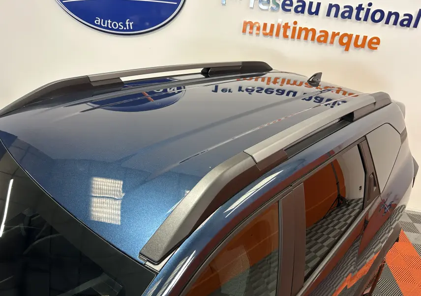 Vue en plongée du toit bleu indigo métallisé du Dacia Bigster 2026 avec barres de toit et vitres latérales teintées.