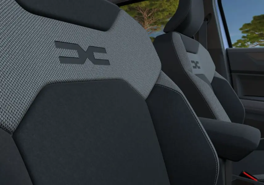 Gros plan sur les sièges avant gris et noirs du Dacia Bigster 2026 avec logo distinctif brodé sur l'appuie-tête.