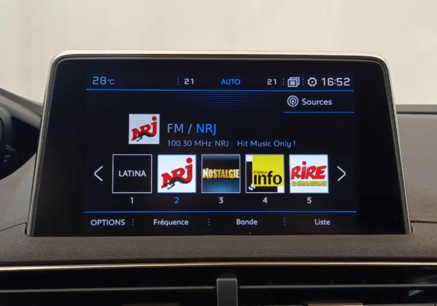 Écran tactile central du tableau de bord du Peugeot 5008 noir, affichant les stations radio FM avec interface moderne.