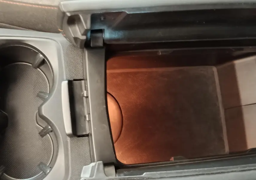 Vue rapprochée de la console centrale noire du Peugeot 5008, montrant un rangement intérieur ouvert et porte-gobelets.