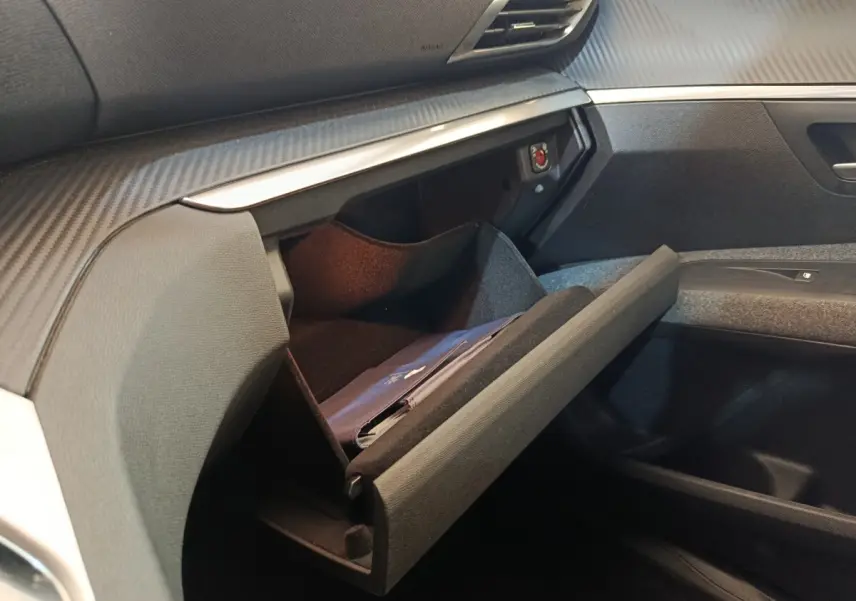 Vue intérieure côté passager du Peugeot 5008 2020 noir, boîte à gants ouverte avec livret visible.