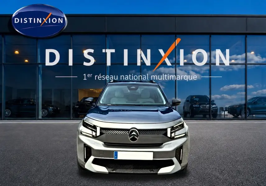Vue avant d'un Citroën C3 Aircross gris mercury 2026 avec calandre noire et phares LED, devant une vitrine Distinxion.