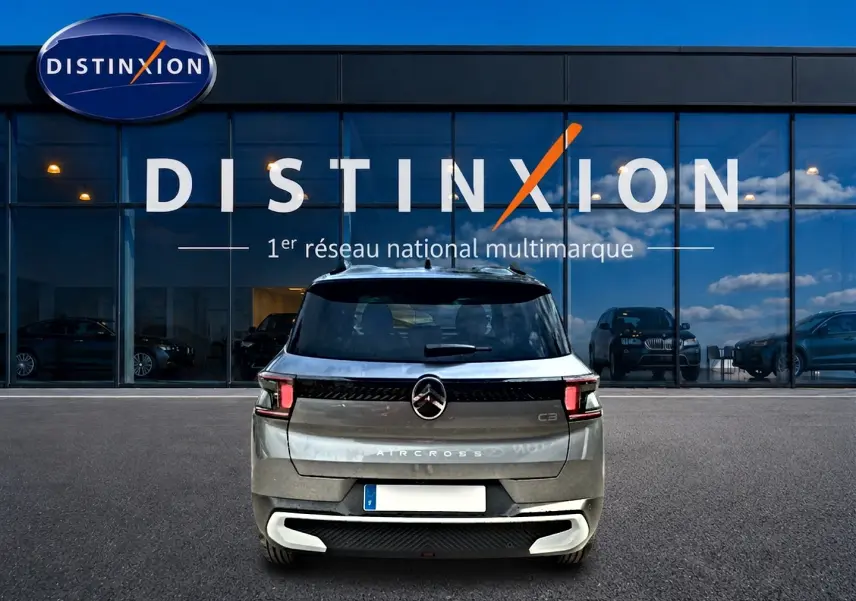 Vue arrière d'une Citroën C3 Aircross gris mercury 2026, avec feux LED et barres de toit visibles devant un showroom Distinxion.