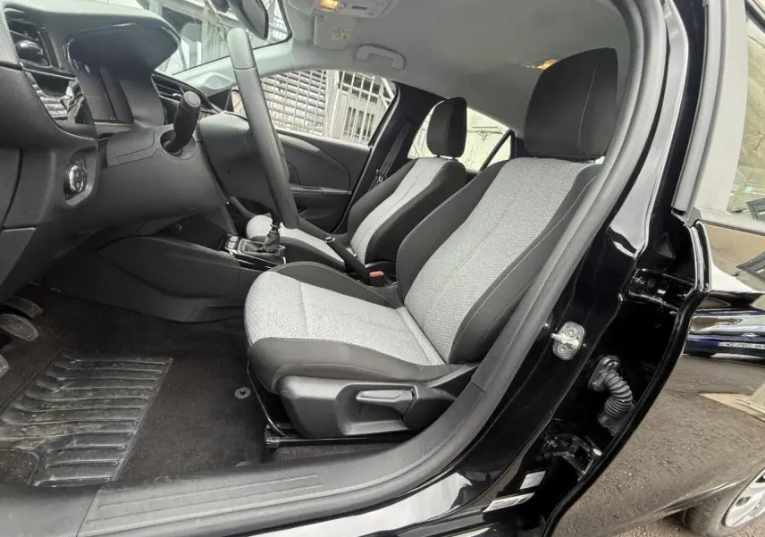 Vue intérieure côté conducteur de l’Opel Corsa 2025 noir karbon, montrant les sièges bi-ton gris et noir et le tableau de bord.