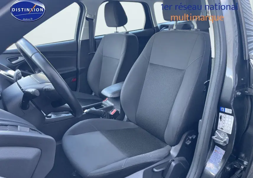 Vue intérieure côté conducteur de la Ford Focus SW 2018 avec sièges tissu noir et portière ouverte gris magnetic metal.