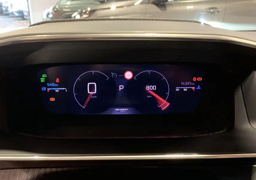 Tableau de bord numérique du Peugeot 2008 gris 2023 affichant vitesse à zéro et compte-tours à 800 rpm.