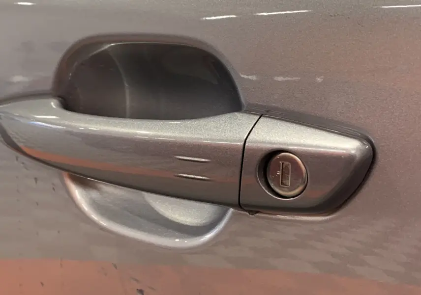 Poignée de porte gris métallisé avec serrure sur Peugeot 2008 BlueHDi 130 EAT8 GT 2023, vue rapprochée côté conducteur.