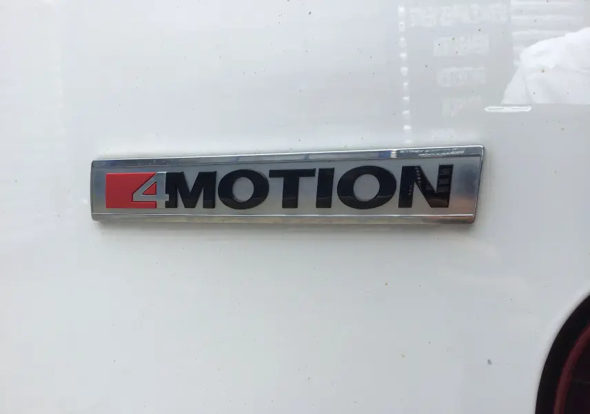 Gros plan sur l'emblème 4MOTION noir et rouge sur la carrosserie blanche d'un Volkswagen Transporter 6.1 Van.