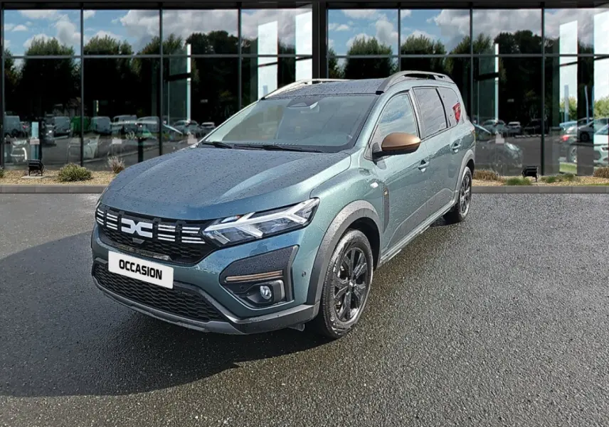 Vue 3/4 avant d'un Dacia Jogger Extreme Hybrid vert avec rétroviseurs bronze et jantes noires sur parking.
