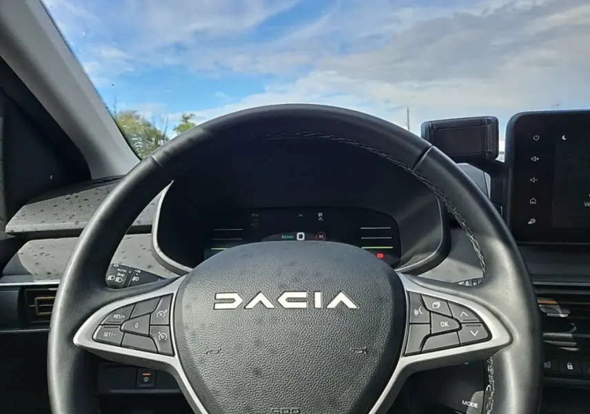 Volant noir avec logo DACIA en gros plan, tableau de bord digital et écran tactile visible à droite, intérieur du Jogger 2024.