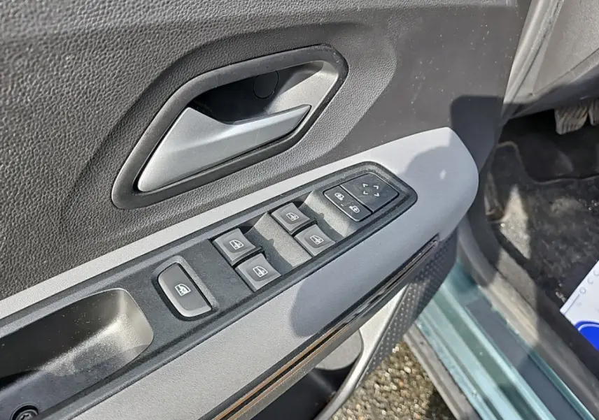 Gros plan sur la commande des vitres électriques côté conducteur d'une Dacia Jogger vert 2024, intérieur noir et gris.