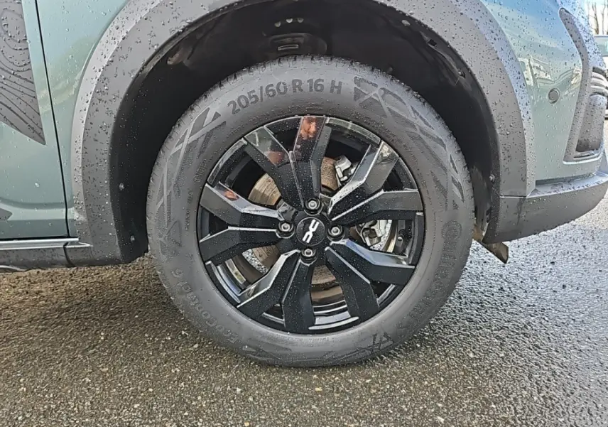 Gros plan sur la roue avant gauche noire du Dacia Jogger vert 2024 avec jante au design moderne.