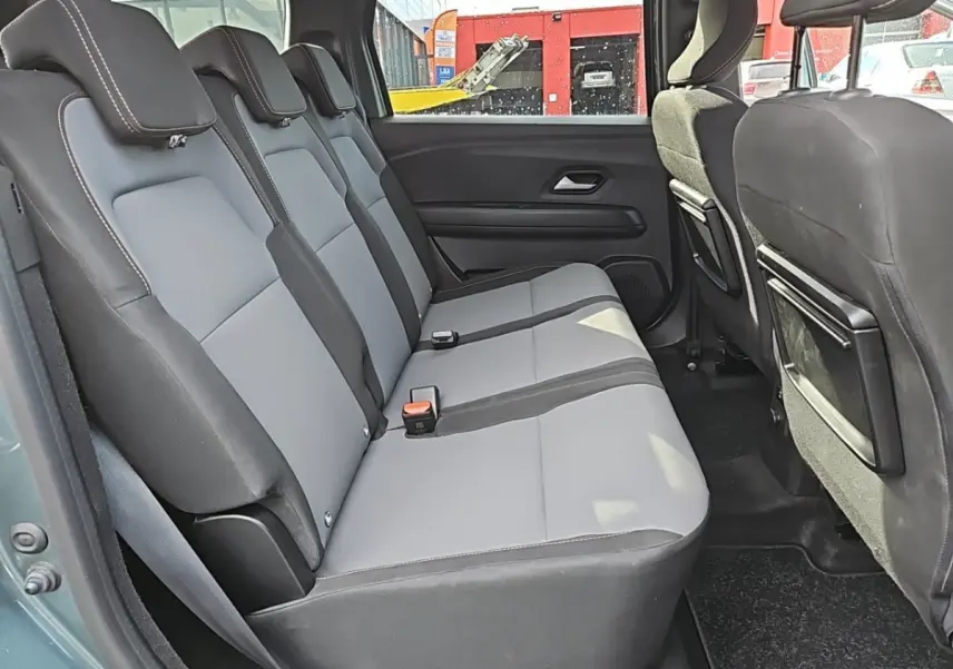 Vue latérale intérieure sur la banquette arrière grise et noire du Dacia Jogger Extreme Hybrid vert 2024.