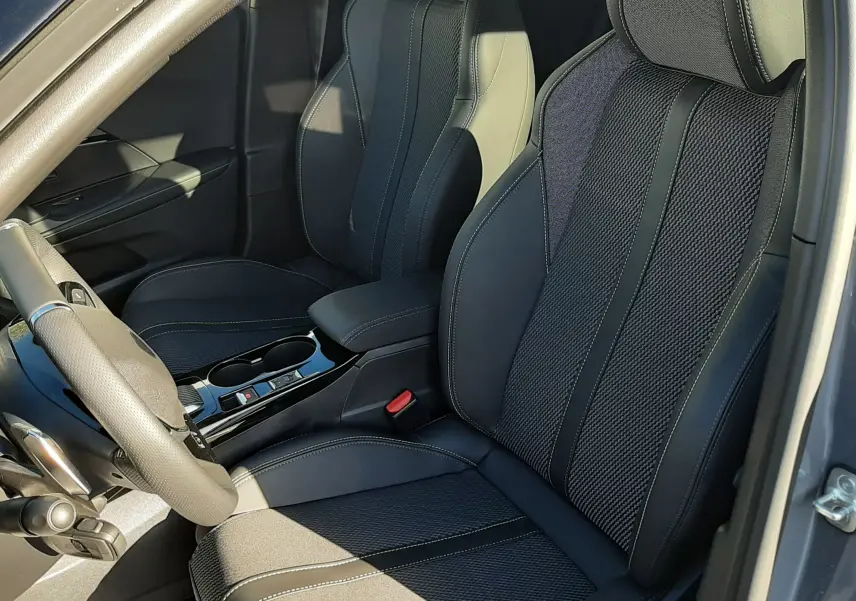 Vue intérieure côté conducteur du Peugeot 2008 gris sélénium 2025, sièges en cuir et tissu noir avec surpiqûres claires.
