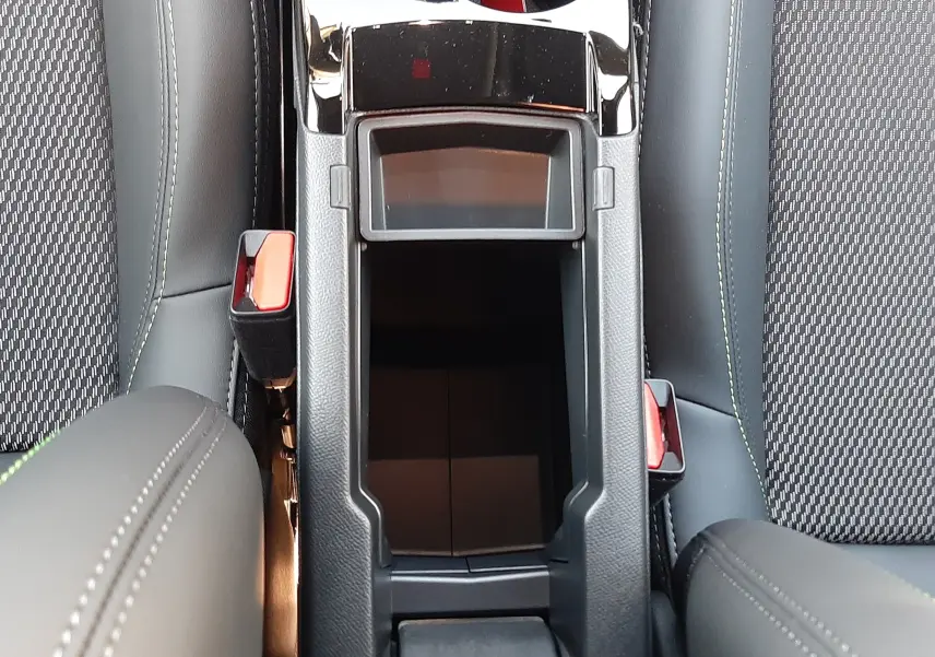 Vue plongeante sur la console centrale noire et les sièges gris foncé à surpiqûres du Peugeot 2008 hybride 2025.