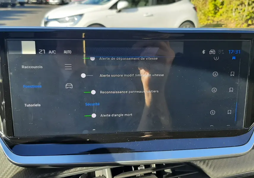 Écran tactile central du Peugeot 2008 1.2 Hybrid 145ch GT 2025 affichant les alertes de sécurité avec reflet extérieur.