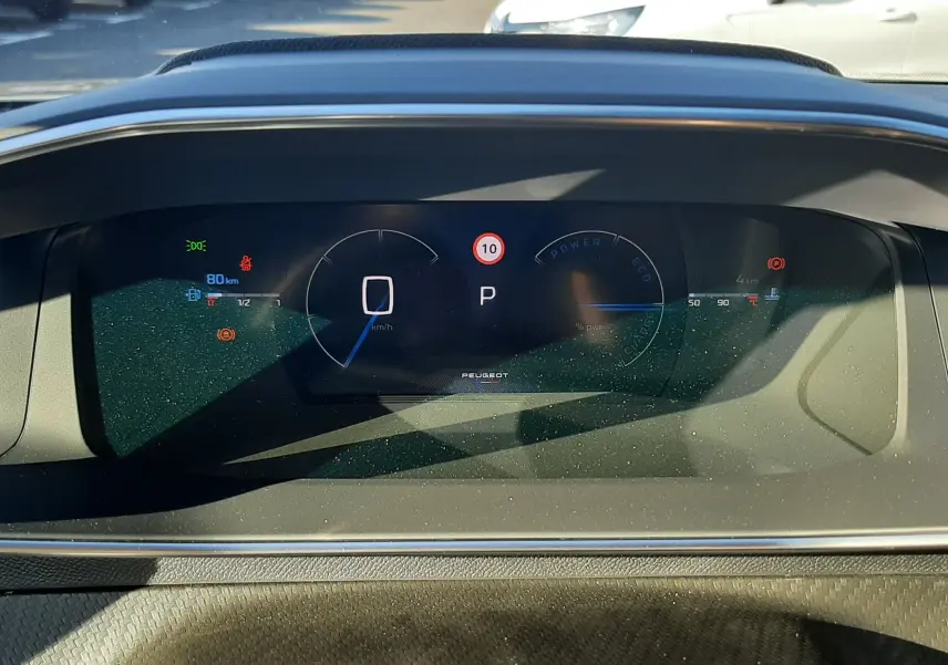 Tableau de bord numérique du Peugeot 2008 1.2 Hybrid 145ch GT, affichant vitesse à zéro et mode parking, intérieur noir.