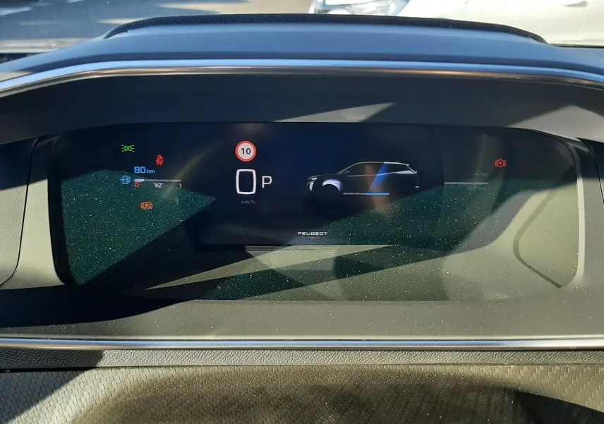 Tableau de bord numérique de Peugeot 2008 gris sélénium, affichant vitesse à 0 km/h et mode parking, vue frontale intérieure.