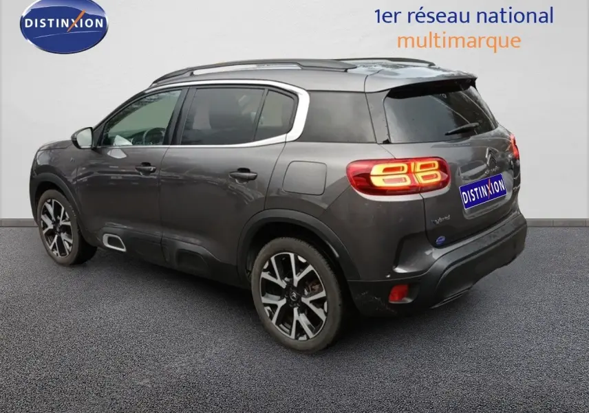 Vue 3/4 arrière droite d'un Citroën C5 Aircross hybride rechargeable gris platinium avec feux arrière allumés.