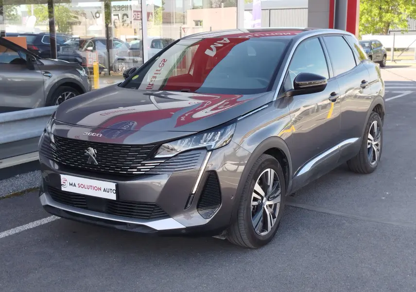 Peugeot 3008 gris Platinium en 3/4 avant droit, avec calandre noire et feux LED distinctifs, stationné devant un showroom.