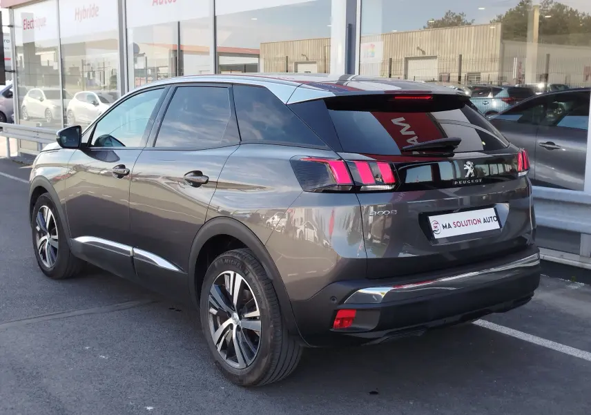 Vue 3/4 arrière droite d’un Peugeot 3008 gris Platinium 2023 avec feux arrière à effet griffes et jantes bi-ton.
