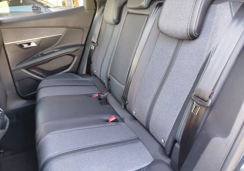Vue intérieure côté gauche des sièges arrière du Peugeot 3008 2023, tissu gris et cuir noir avec surpiqûres bleues.