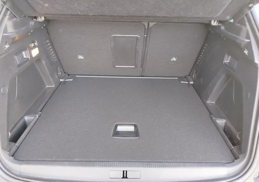 Vue intérieure du coffre spacieux et propre du Peugeot 3008 gris Platinium, avec banquette arrière rabattue partiellement.