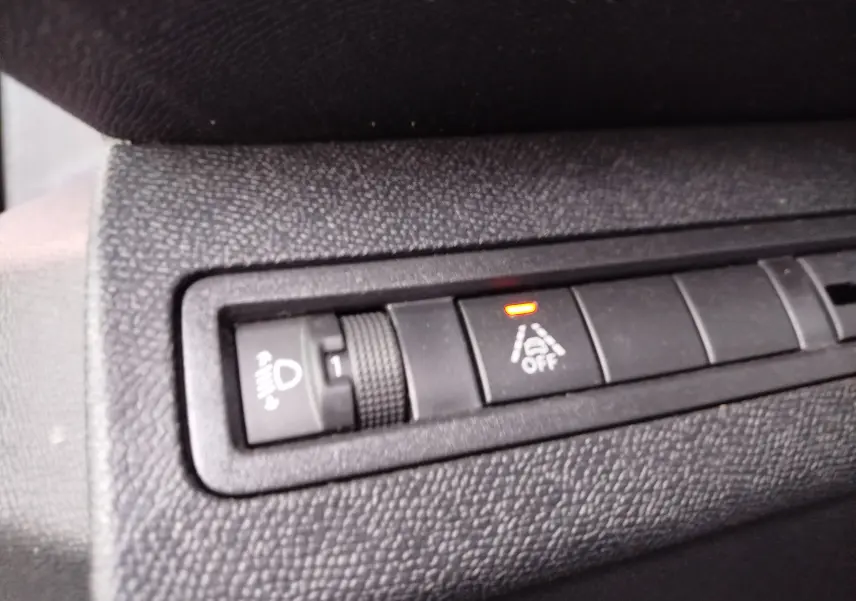 Gros plan sur les commandes intérieures noires du Peugeot 3008 2023, avec bouton d'alerte de maintien de voie allumé.